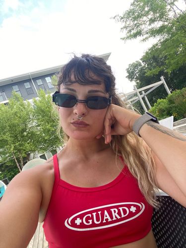 Woman wearing a red lifeguard swimsuit with the word GUARD in white.
