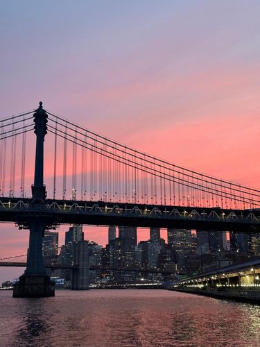 Manhattan Bridge at sunset with a vibrant pink and orange sky.